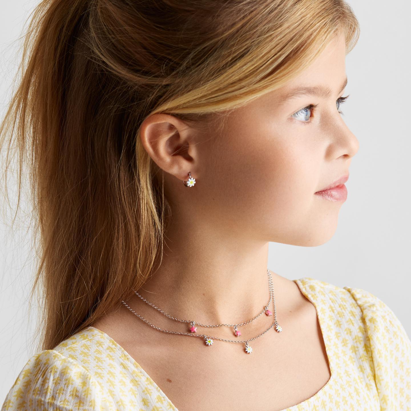 Een meisje met kindersieraden waaronder kinderoorbellen en een kinderketting