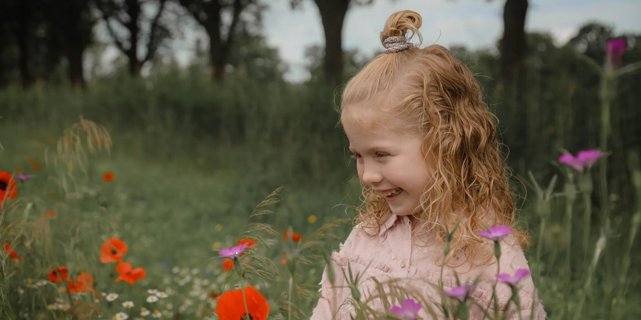 Meisje in een bloemenveld met in het haar een vrolijk staartje met daarin een Banditz elastiek.