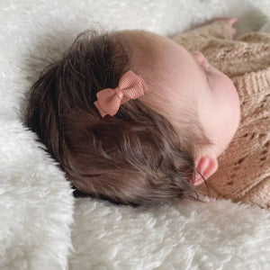 Babymeisjes met klein babyhaarspeldje met strikje in het haar.