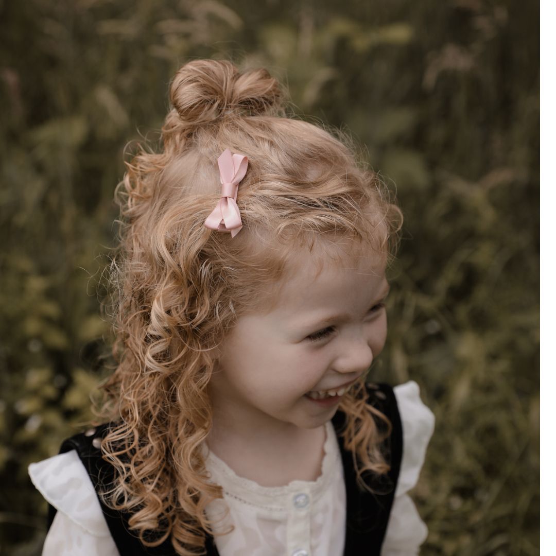 Peuter/kleuter meisje met een haarspeldje met satijnen strikje in de kleur roze in het haar.