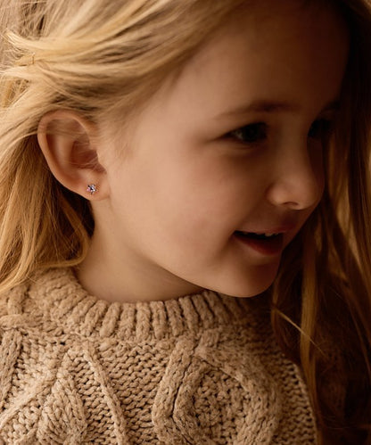 Meisje met een setje metaalvrije oorbellen van medical plastic in. Van het merk Blomdahl. De oorbelletjes zijn in de vorm van sterretjes en hebben de kleur paars.