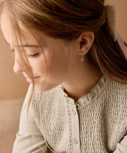 Een tienermeisje met oorbellen Blomdahl titanium goudkleurige oorringen 14 mm. bicone crystal in het oor.